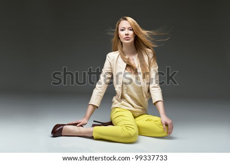 beautiful blonde girl in stylish clothes, yellow pants leather jacket and high heels. Fashion model posing at studio