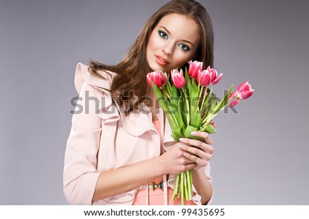 young brunette woman in pink coat holding flowers