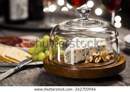 Bleu Cheese and Walnuts Under a Cheese Dome with Charcuterie and Crackers and Twinkly Lights in the Background