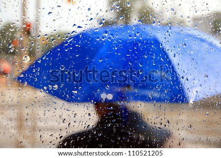A man holding a blue umbrella during a rainy day