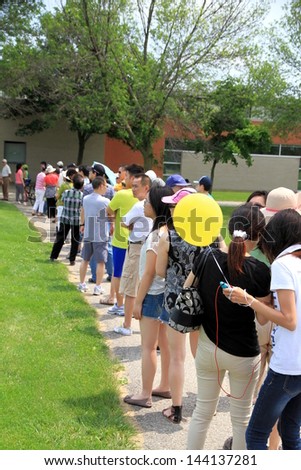 TORONTO - JUNE 23: People lining up in a park in a hot day of Summer on June 23, 2013 in Toronto. Toronto, has a humid continental climate with warm and humid summers.