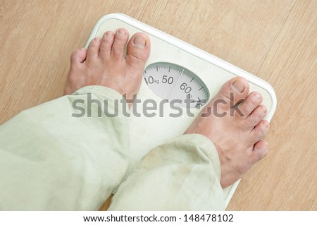 Man standing on weight scales with bare foot