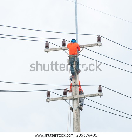 Electrician lineman repairman worker at climbing work on electric post power pole.
