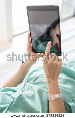 Mature female patient used tablet on bed in hospital