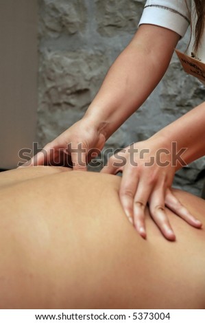 Massage detail with woman\'s hand on man\'s back.