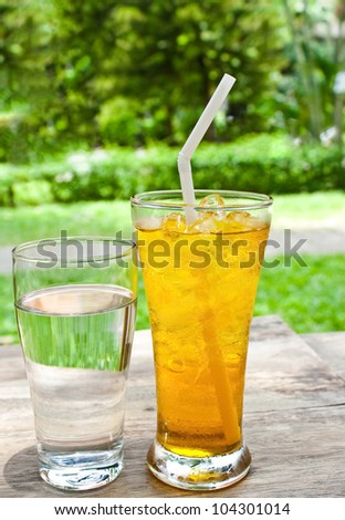 a glass of drinking water and iced Chrysanthemum tea (flower tea) on wooden table