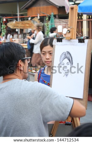 CHIANG MAI,THAILAND-JUNE 23 : an artist who draw portraits for customer, 30 minute wait for a picture  ,On June 23, 2013 in Chiang Mai, Thailand.