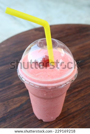 strawberry smoothie in plastic glass on wooden table. feeling fresh with iced drink