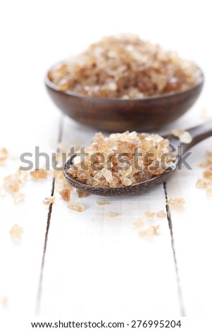 rock sugar in wooden spoon and wooden bowl on white wooden background