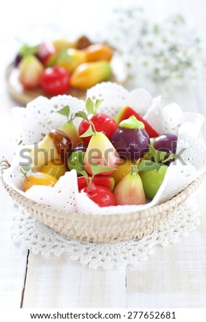 thai dessert made from stirred bean mixed with sugar and coconut covered with glass jelly.  Deletable imitation fruits in wicker basket on white wooden background.  Thai dessert..