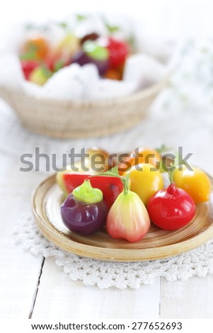 thai dessert made from stirred bean mixed with sugar and coconut covered with glass jelly.  Deletable imitation fruits in wicker basket on white wooden background.  Thai dessert..