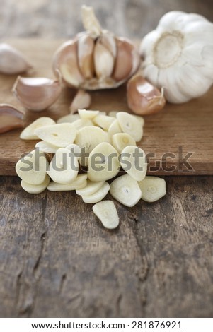 sliced garlic, garlic clove, garlic bulb place on chopping block on vintage wooden backgorund