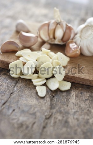 sliced garlic, garlic clove, garlic bulb place on chopping block on vintage wooden backgorund