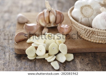sliced garlic, garlic clove, garlic  bulb in wicker basket place on chopping block on vintage wooden background