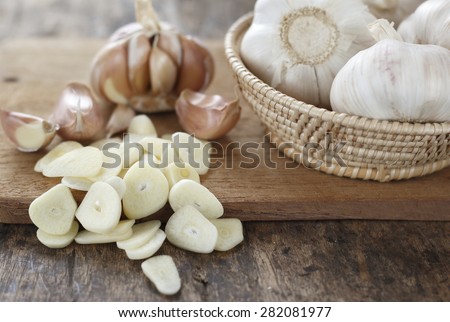 sliced garlic, garlic clove, garlic  bulb in wicker basket place on chopping block on vintage wooden background