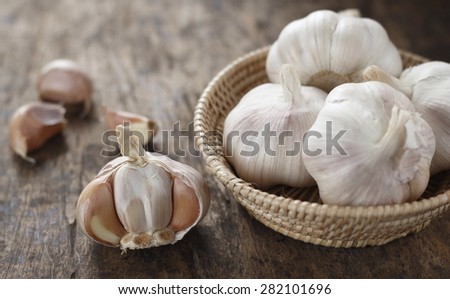 garlic  bulb in wicker basket, garlic cloves on old wooden background