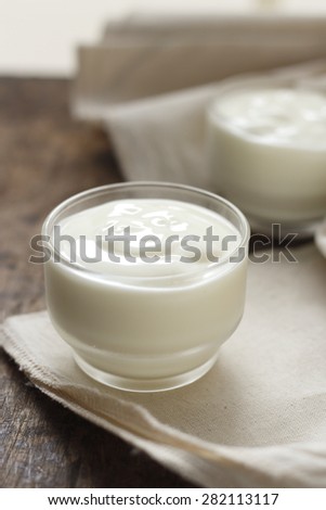 yogurt in glass on cotton cloth place on old wooden background. plain yoghurt.