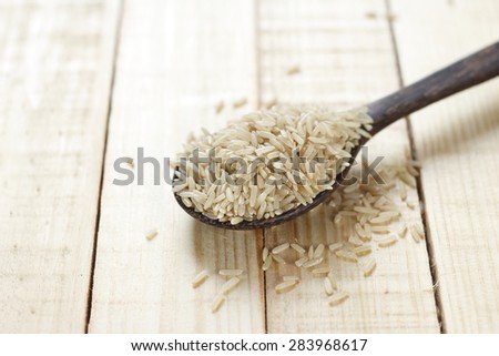 uncooked brown rice in wooden spoon place on wooden background. organic product, organic brown rice.