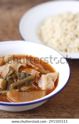 hot and sour, mixed  vegetable in the thai style containers of galvanized dish and small bowl and cooked brown rice. hot and sour taste of a kind of thai curry.Thai food. Thai. curry. vegetarian food.