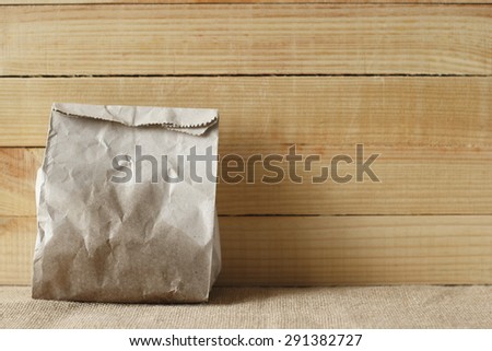 paper bag of some food in front of wooden background.