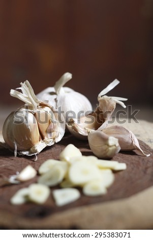 sliced garlic, garlic clove, garlic bulb on chopping block made of a log