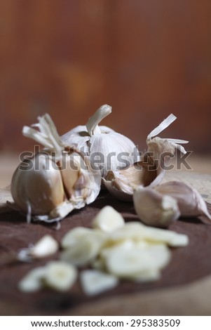 garlic slice, garlic clove, garlic bulb on chopping block made of a log