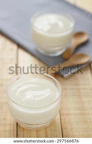 yogurt in glass cup on wooden background with grey cotton and wooden spoon. plain yoghurt. yogurt. yoghurt.