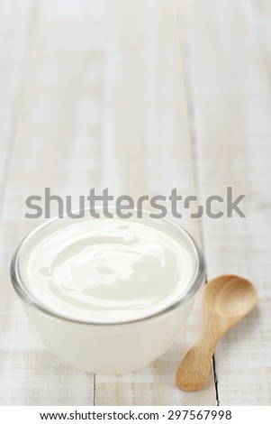 yogurt in glass cup on wooden background with  wooden spoon. plain yoghurt. yogurt. yoghurt.