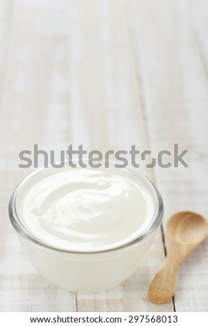 yogurt in glass cup on wooden background with  wooden spoon. plain yoghurt. yogurt. yoghurt.