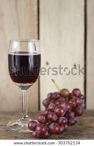 glass of red wine (wine cooler) and fresh grape on wooden background.
