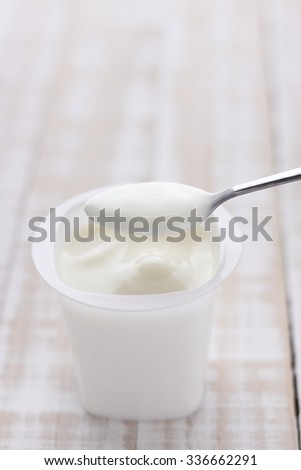 plain yogurt in white plastic cup on wooden white background. white yoghurt. plain yogurt. yoghurt.