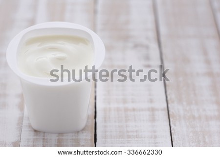 plain yogurt in white plastic cup on wooden white background. white yoghurt. plain yogurt. yoghurt.