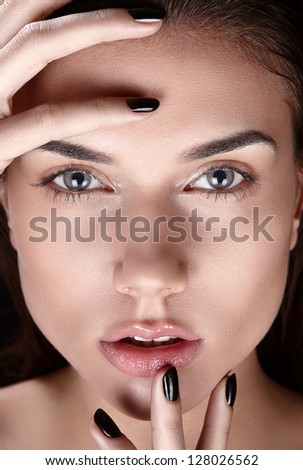 Detailed beauty shot of young woman. Pure healthy shiny skin, perfect black nails manicure, natural looking makeup, clean. Touching her face with hands. Close up.