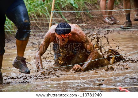 DALLAS, TEXAS - SEPTEMBER 15: Unidentified race participant crawls through a mud pit in the Dash of the Titans Mud Run Race on September 15, 2012 in Dallas, Texas.
