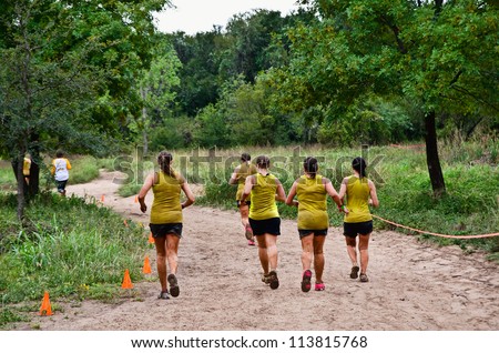 DALLAS, TEXAS - SEPTEMBER 15: Unidentified team participants run along the course near finish in the Dash of the Titans Mud Run Race on September 15, 2012 in Dallas, Texas.