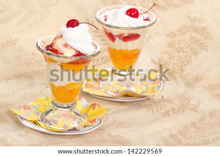 Vanilla peach melba ice cream with whipped cream and cherries in glass bowls
