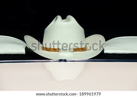 Cowboy hat displayed on the back of a car window against dark background, vintage filter effect