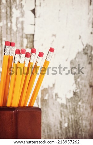Group of eraser ends of yellow pencils in pencil holder, gray wooden background with copy space, vintage filter effects