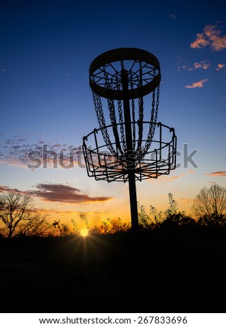 Disc golf basket in the park at sunset or sunrise
