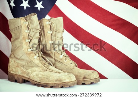 Old combat boots with American flag in the background. Vintage filter effects.
