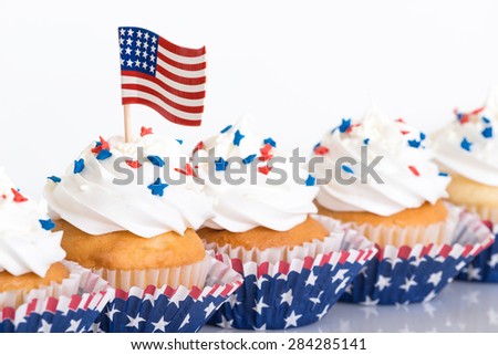Row of patriotic cupcakes decorated with sprinkles and American flag, shallow depth of field