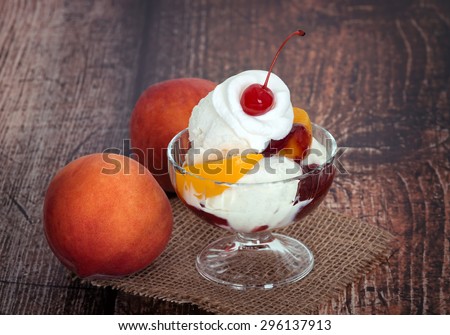 Vanilla peach melba ice cream with peach fruits on wooden dark vintage background