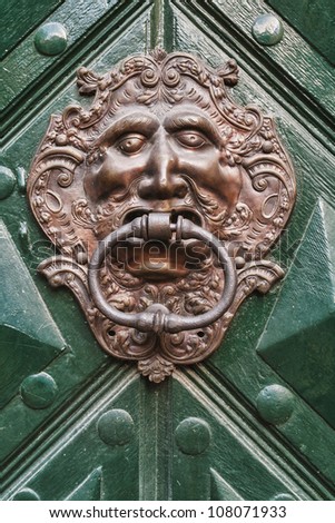 close-up of lion headed door knocker on green painted wooden door