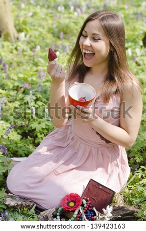 beautiful smiling  girl is holding cup with strawberries