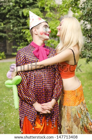 Portrait of a smiling man dressed like a clown  presented a balloon to a happy girl with butterfly makeup