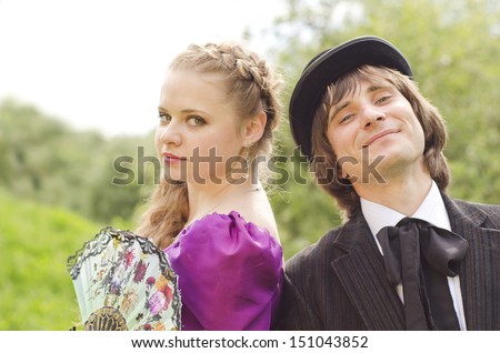 Portrait of a beautiful fashionable woman with a fan and an young smiling gentleman