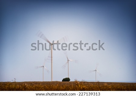 Windfarm - wind turbines working on the field at dusk.