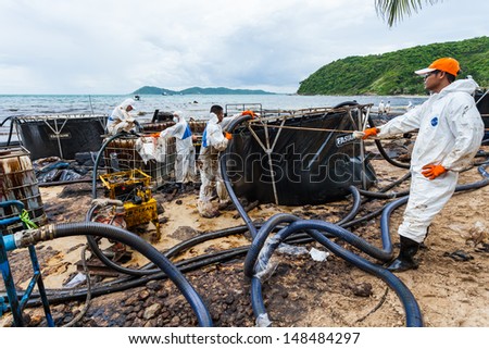 RAYONG,THAILAND-July 31 : Workers using the suck machine to suck up the crude oil and release in safe tank on oil spill accident on Ao Prao Beach at Samet island on July 31,2013 in Rayong,Thailand