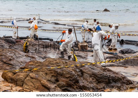 RAYONG,THAILAND-July 31 : The workers use high pressure water jet clean the crude oil from stone on oil spill accident on Ao Prao Beach at Samet island on July 31,2013 in Rayong,Thailand