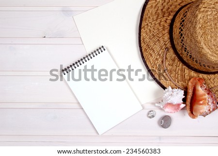 Open white notepad with hat on the wooden table. Mock up on the wood. Shells.